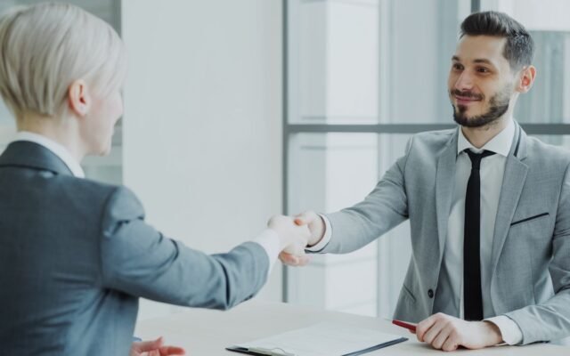 Two professionals shaking hands after a job interview in a modern office