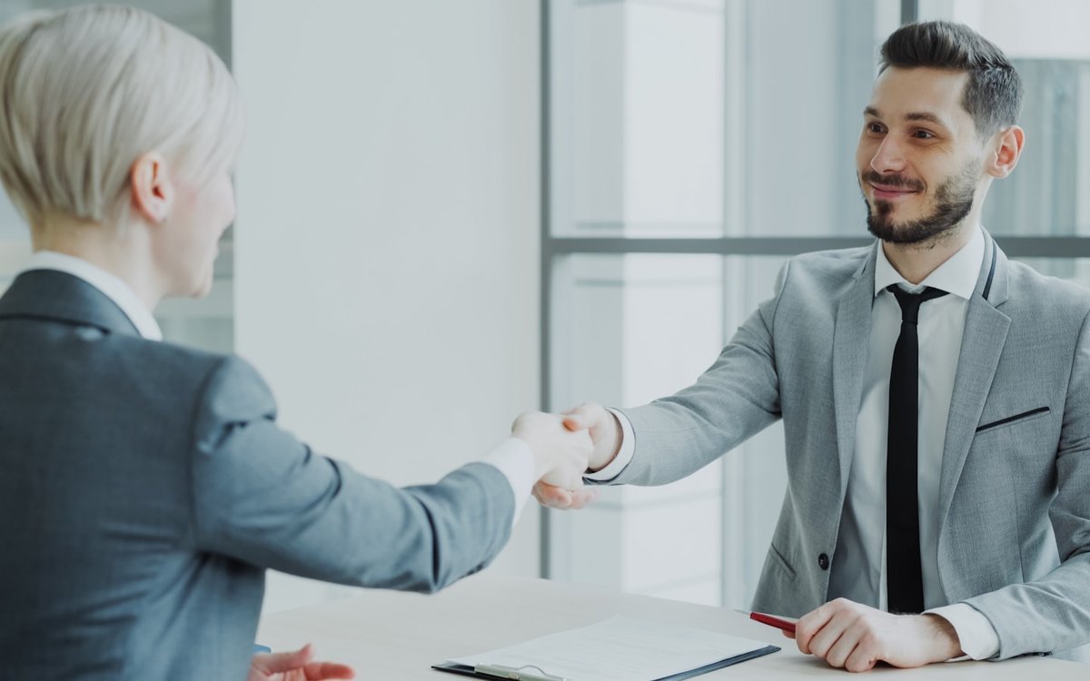 Two professionals shaking hands after a job interview in a modern office