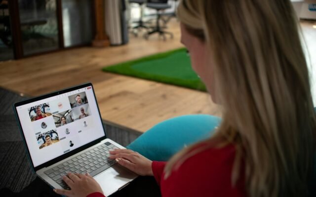 Person on a video call with a team, coordinating work on a laptop