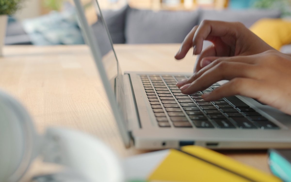 Close-up of hands typing on a laptop keyboard