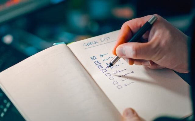 Hand checking off items on a handwritten checklist in a notebook